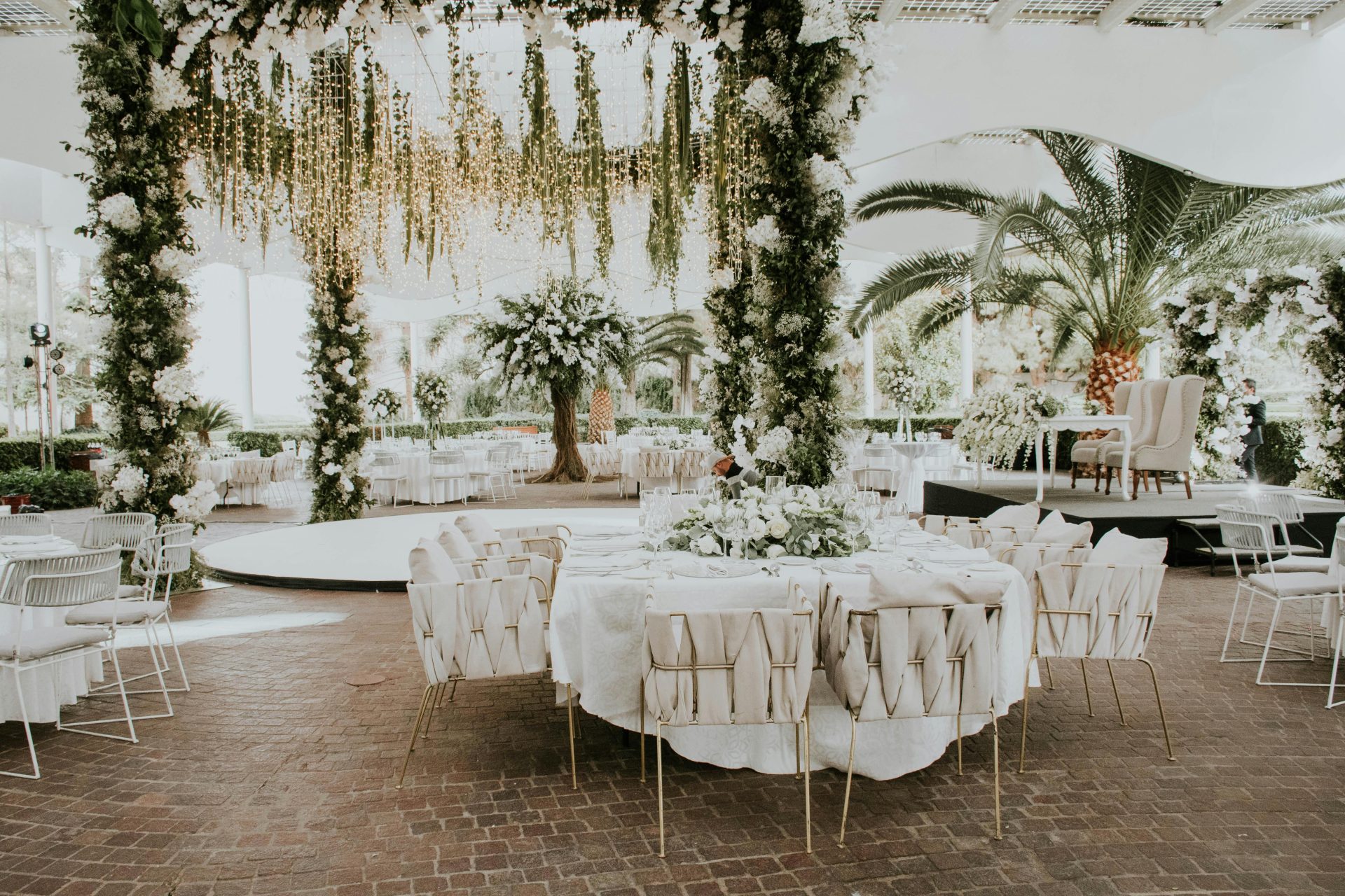Atemberaubendes Outdoor-Hochzeitsambiente mit Blumendekorationen, eleganten Sitzgelegenheiten und stimmungsvoller Beleuchtung.