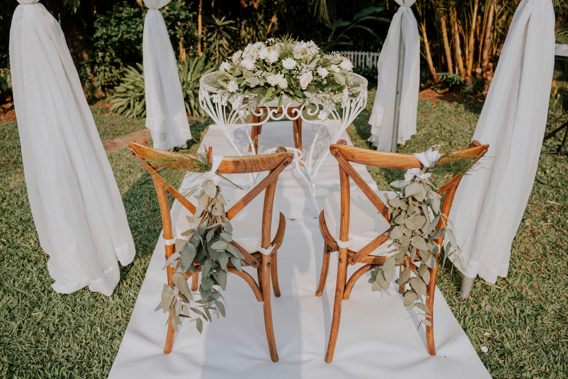 Eine elegante, im Freien gestaltete Hochzeitslocation mit weißen Blumenbögen und Stühlen.