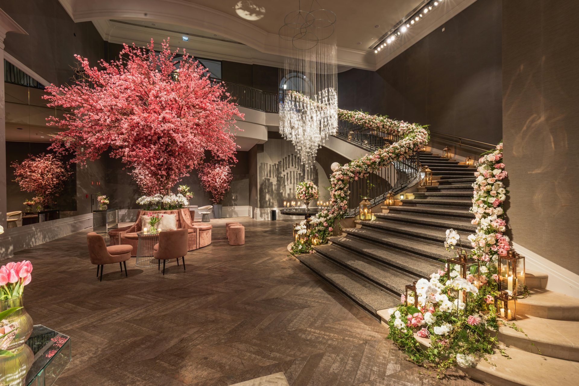 Eine prachtvolle Hotellobby mit exquisiten Blumendekorationen, einer Wendeltreppe und eleganten Kronleuchtern.