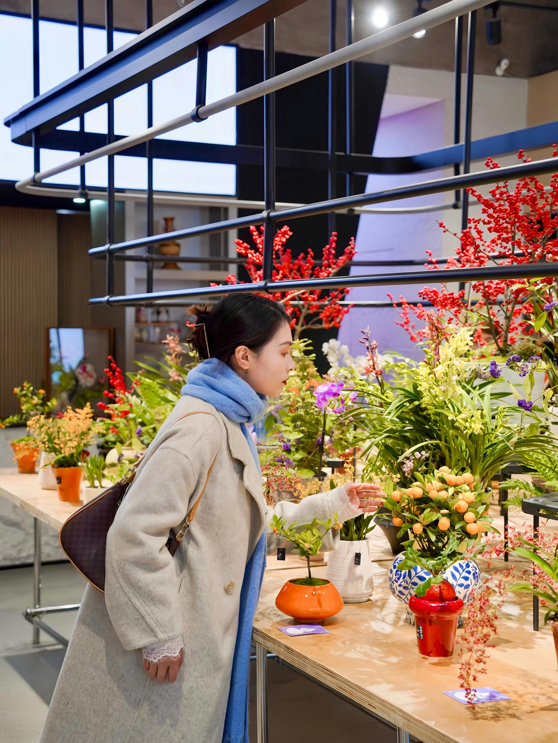 Eine Frau bewundert farbenprächtige Blumenarrangements in einem Innenraum, die ein Fest für die Sinne bieten.