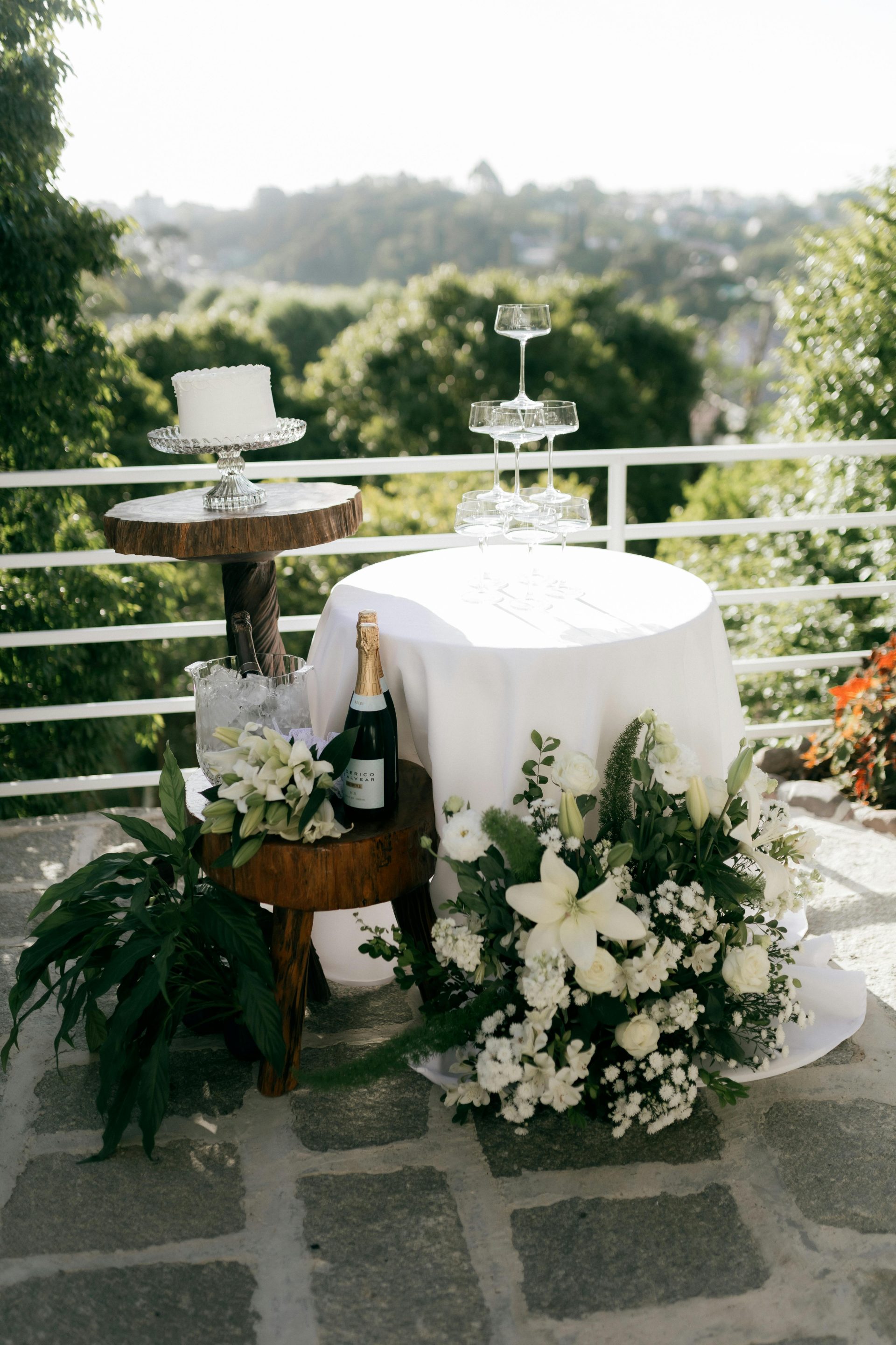 Wunderschöner, im Freien gedeckter Hochzeitskuchentisch mit Blumenarrangements und Champagner.